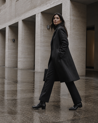 Woman wearing the black Aquatalia Ulyssa nappa-leather zip-up boots in a rain-darkened modern Italian arcade