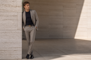 Man wearing the exact black Gucci full-grain leather belt with gold Double G buckle in modern Italian architecture