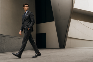 Man wearing the exact Marco Di Milano black pirarucu whole-cut oxford with a charcoal suit in modern Italian architecture