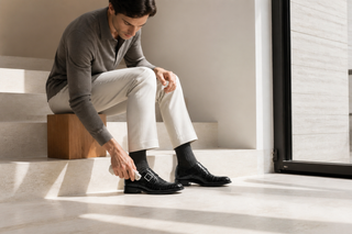 Man caring for the exact black Belvedere ostrich-and-leather single monk strap in a modern limestone interior