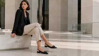 Woman in black leather slingback flats seated in a modern Milan office atrium