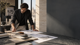 Architect reviewing plans and material samples in a contemporary Milan studio