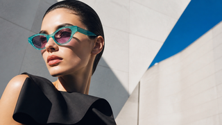 Model wearing Gucci GG1298S green mother-of-pearl sunglasses in modern Italian architecture