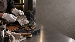 Gloved artisan comparing unbranded leather texture samples in a modern Milan materials studio.