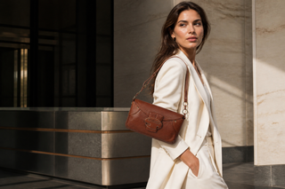 Woman carrying the exact Sergio Rossi chocolate-brown leather baguette bag in an Italian architectural setting