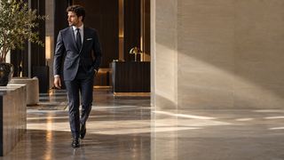 Hospitality professional in dark tailoring walking through a contemporary Italian hotel lobby