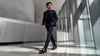Model wearing black Emilio Franco Marco leather Oxfords in a modern architectural lobby