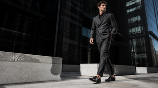 Model wearing Mezlan Milani black leather loafers in a contemporary Milan business district