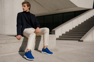 Man wearing the exact Cesare Paciotti blue suede sneaker in a modern European architectural setting