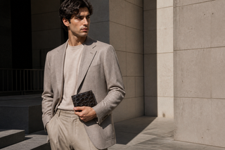 Model holding a Tuzzi Uomo genuine crocodile bill fold wallet in modern Milan architecture