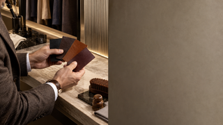Man comparing black, brown, cognac and oxblood leather color swatches in a modern dressing room.