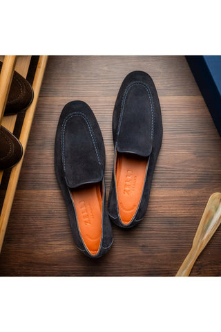Zelli Italia Bruno navy Italian suede penny loafers with a round toe and orange leather insole on a wooden surface.